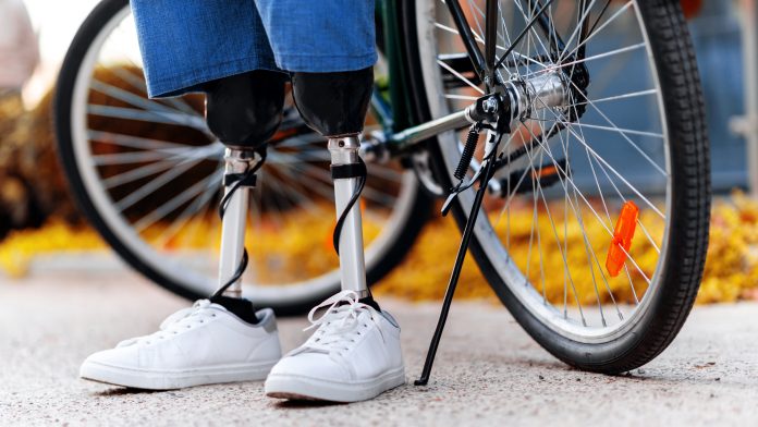 view-man-with-prosthetic-legs-white-sneakers-standing-his-bicycle