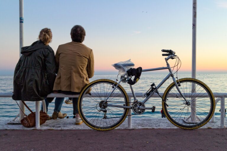 Un couple regarde la mer sur la promenade des anglais avec un vélo à côté d'eux
