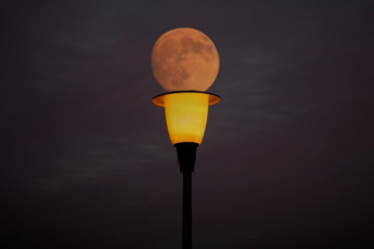 un éclairage public en dessous de la lune.
