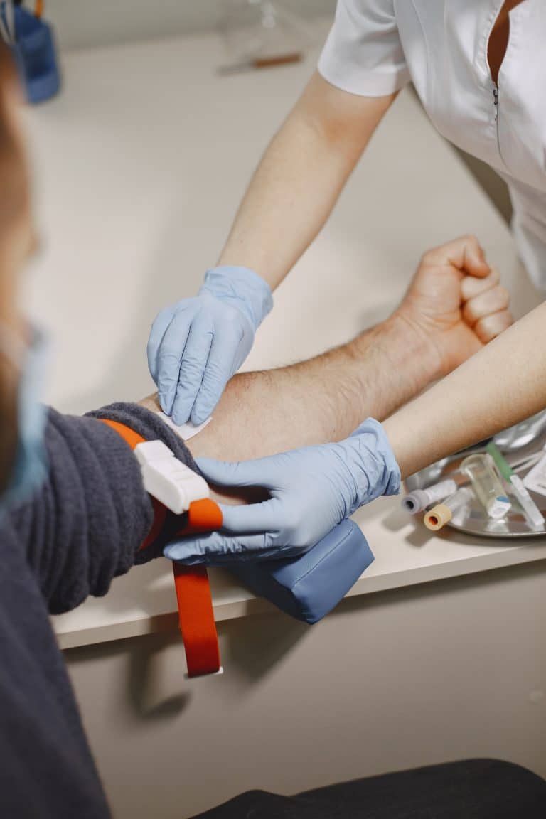 Une infirmière prépare une prise de sang sur un patient.
