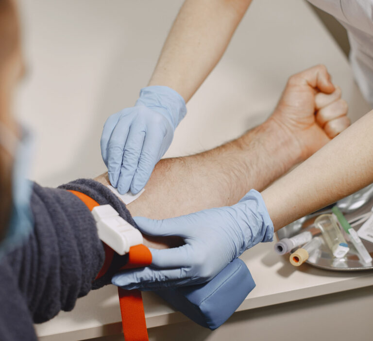 Une infirmière prépare une prise de sang sur un patient.