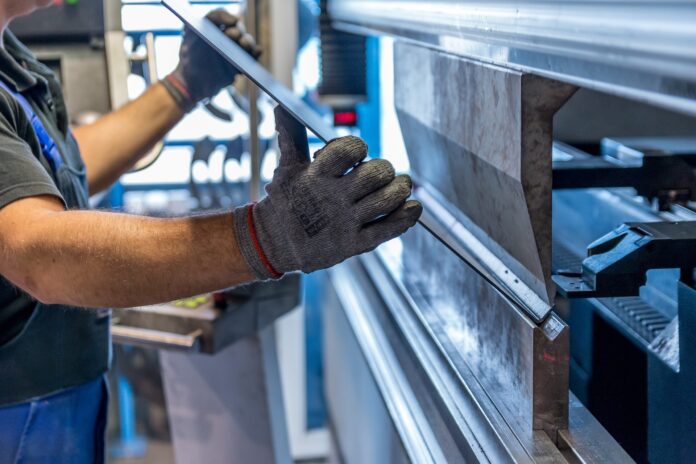 Un ouvrier travail avec une cintreuse dans une usine.