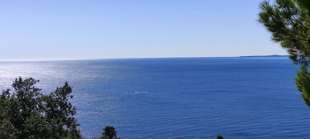 La mer Méditerranée avec des petits voiliers sous le soleil.