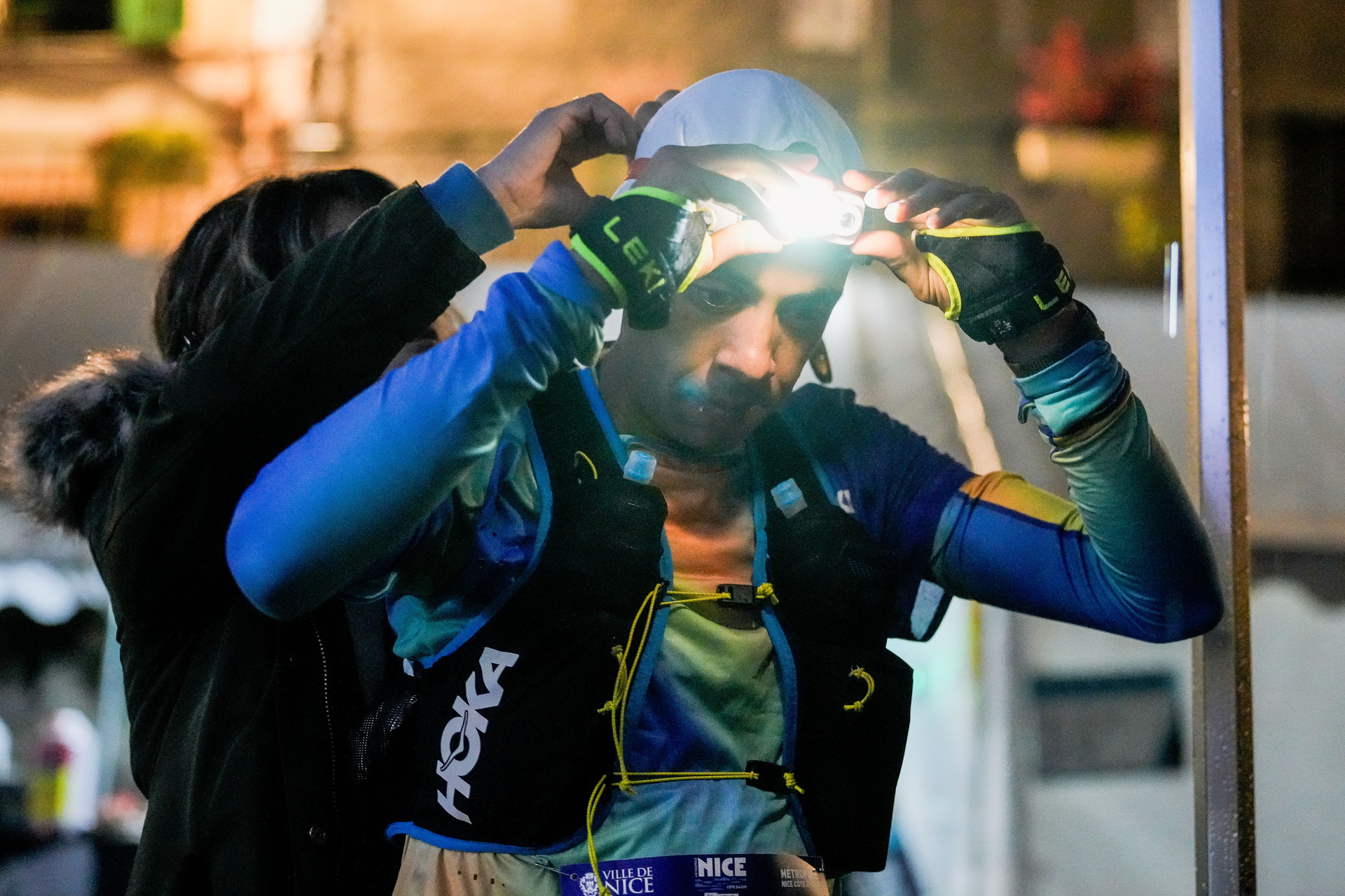 Un homme prépare sa lampe frontale dans de partir courir l'UTMB Nice Côte d'Azur 2024.