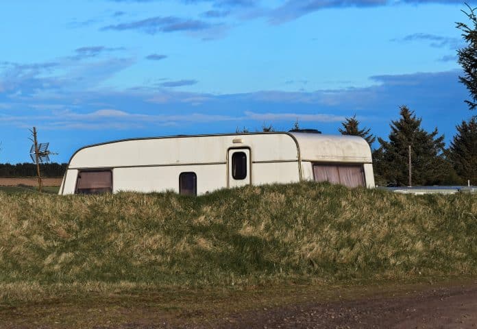 Une caravane cachée derrière un talus.
