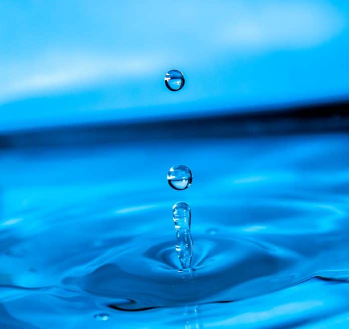 une goutte d'eau qui tombe dans une flaque bleue.