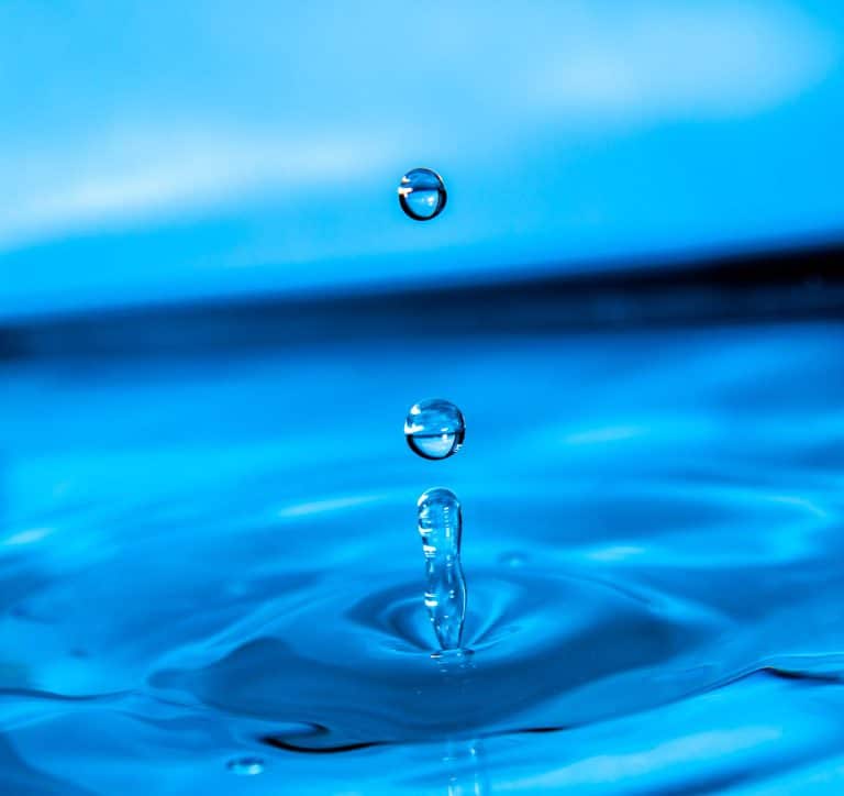 une goutte d'eau qui tombe dans une flaque bleue.