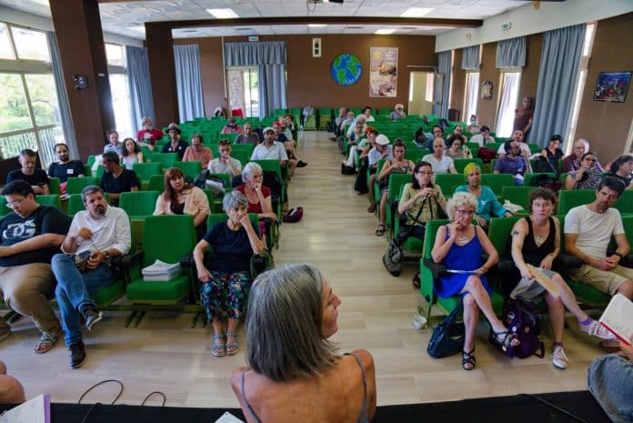 L'assemblée Reprenons la main avec une centaine de personnes assises sur des chaises vertes.