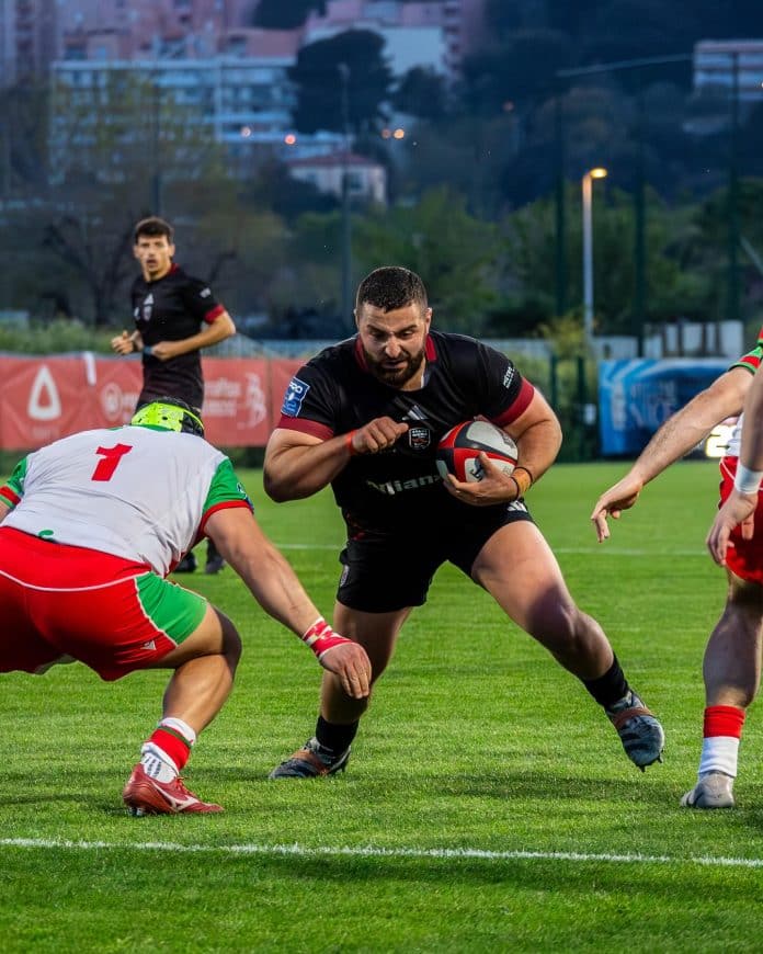 Un joueur du Stade Niçois se prépare à se faire plaquer en match, ballon en main, par un joueur du Biarritz Olympique.