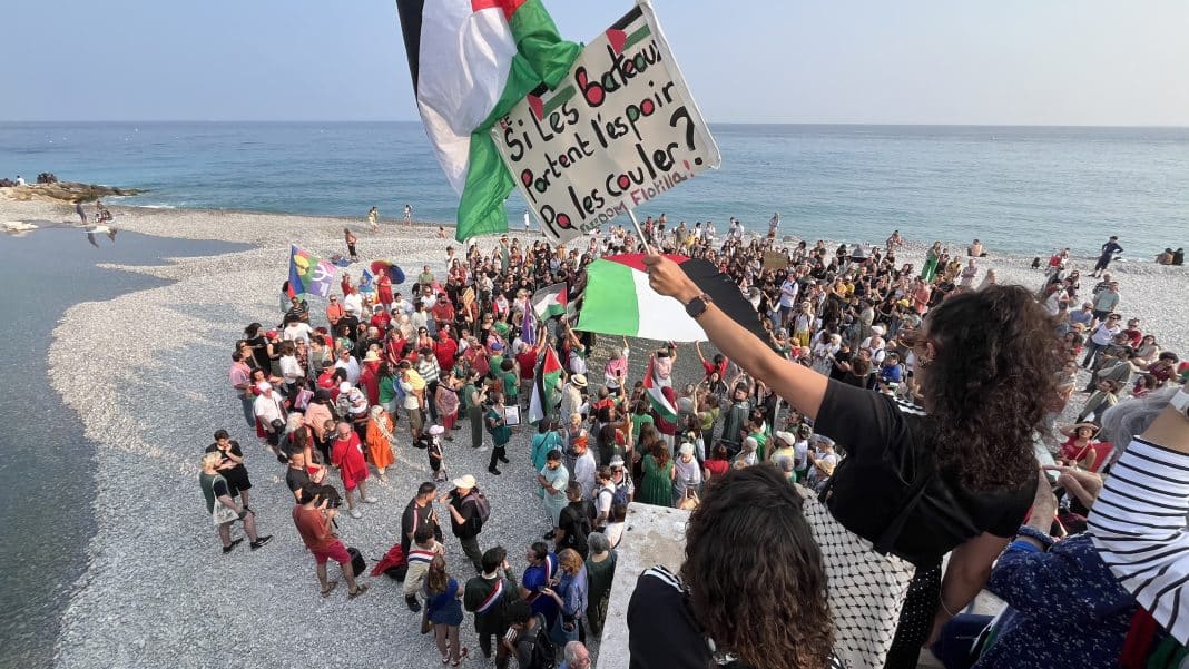 Rassemblement contre l'interception du navire Madleen, sur la plage du Centenaire. Les gens sont habillés aux couleurs de la Palestine