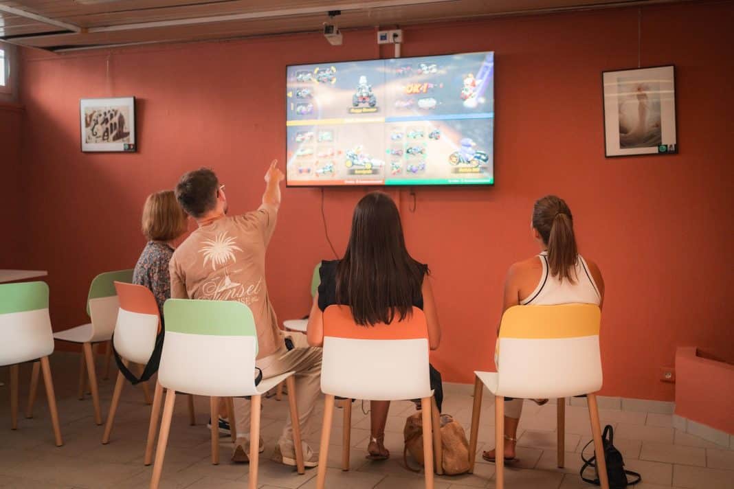 Des jeunes regardent un écran et jouent à un jeu vidéo.