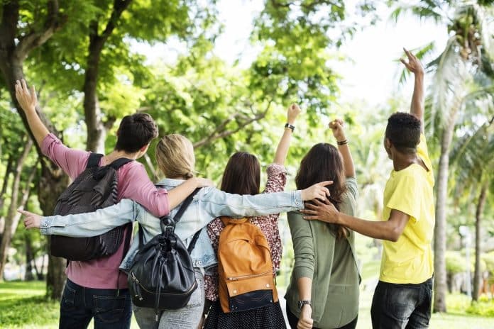 Des étudiants dans un parc avec leurs sacs à dos.
