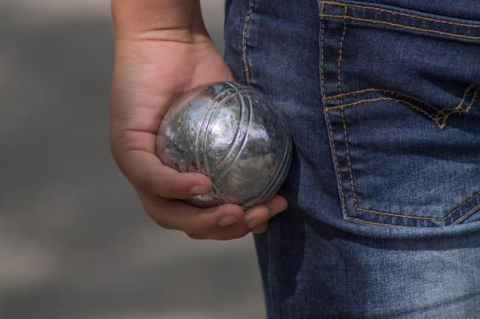 Un joueur de pétanque avec une boule à la main.