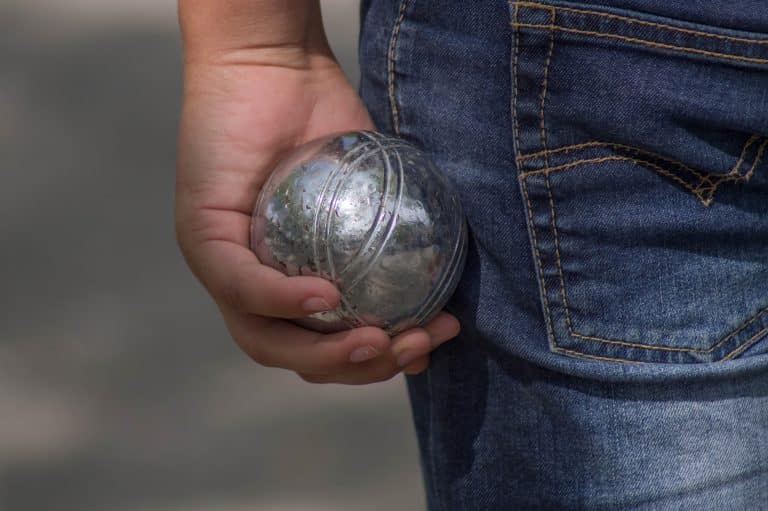 Un joueur de pétanque avec une boule à la main.