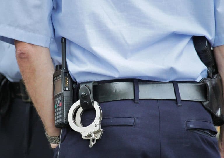 Un agent de police de dos avec des menottes à la ceinture.
