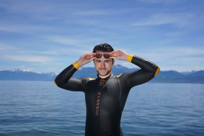 Le nageur Suisse Noam Yaron en combinaison noir aux liserés jaunes au bord de l'eau avec ses lunettes de plongée noir.
