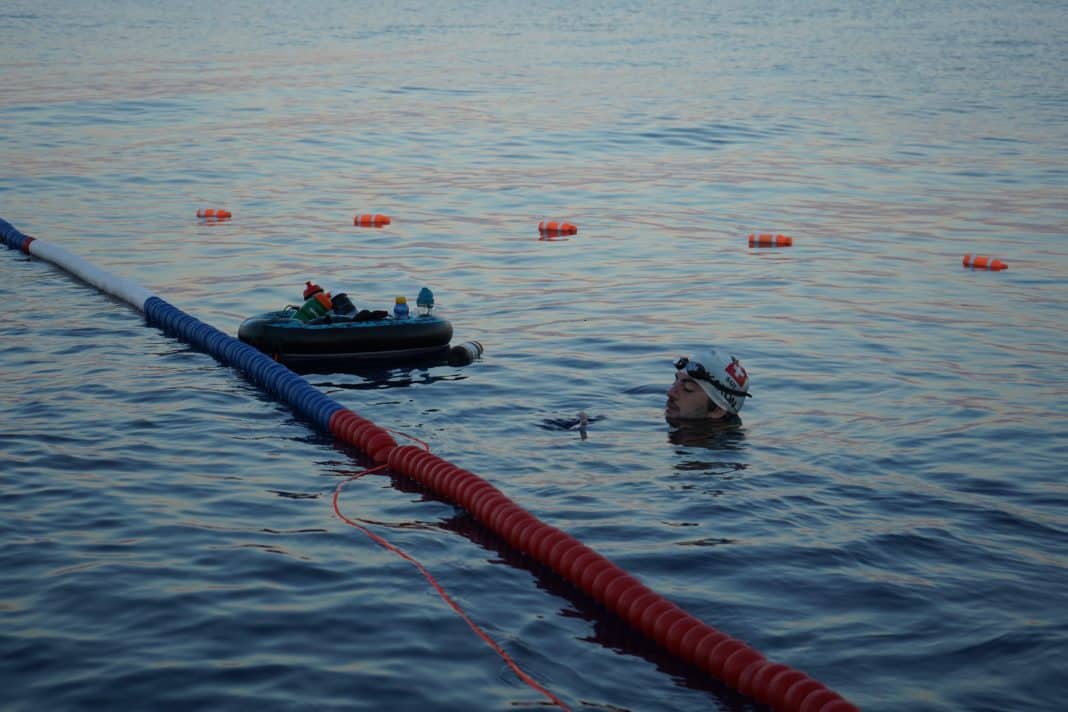 Le nageur Suisse Noam Yaron au départ de sa traversée entre Calvi et Monaco en combinaison intégrale derrière son bateau d'assistance.