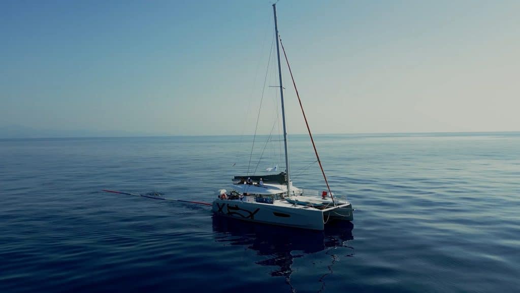Noam Yaron nage derrière un catamaran qui lui donne le cap à suivre.  