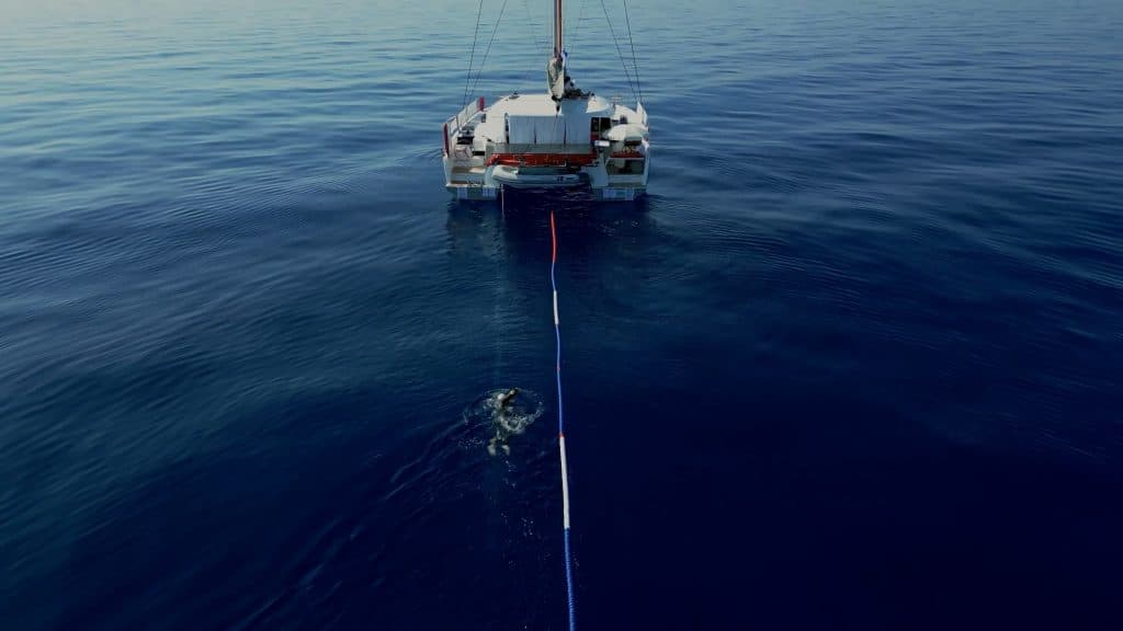 Noam Yaron nage derrière un catamaran qui lui donne le cap à suivre.