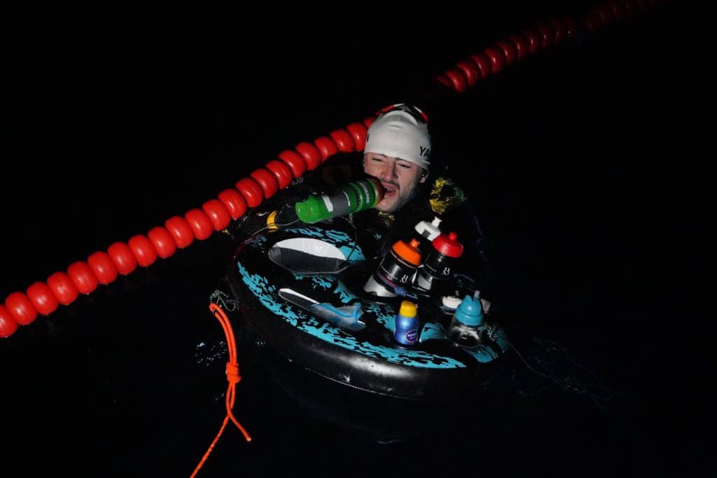 Swiss swimmer Noam Yaron at the start of his swim between Calvi and Monaco in a wetsuit behind his support boat.