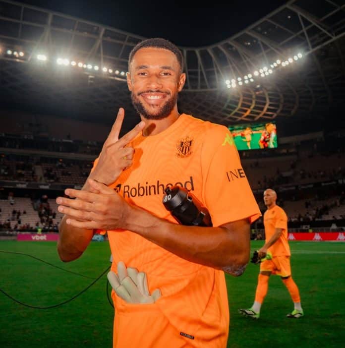 Le gardien de l'OGC Nice Yehvann Douf dans sa tenue orange fait le V de la victoire avec ses doigts.