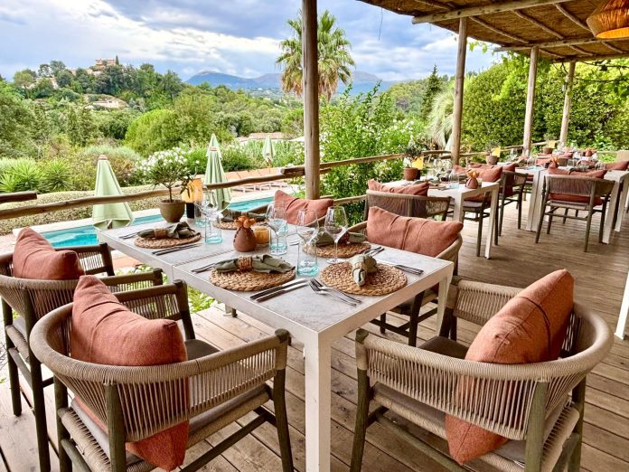 Le restaurant Toile Blanche et ses tables à l'extérieur dans un cadre champêtre très arboré.