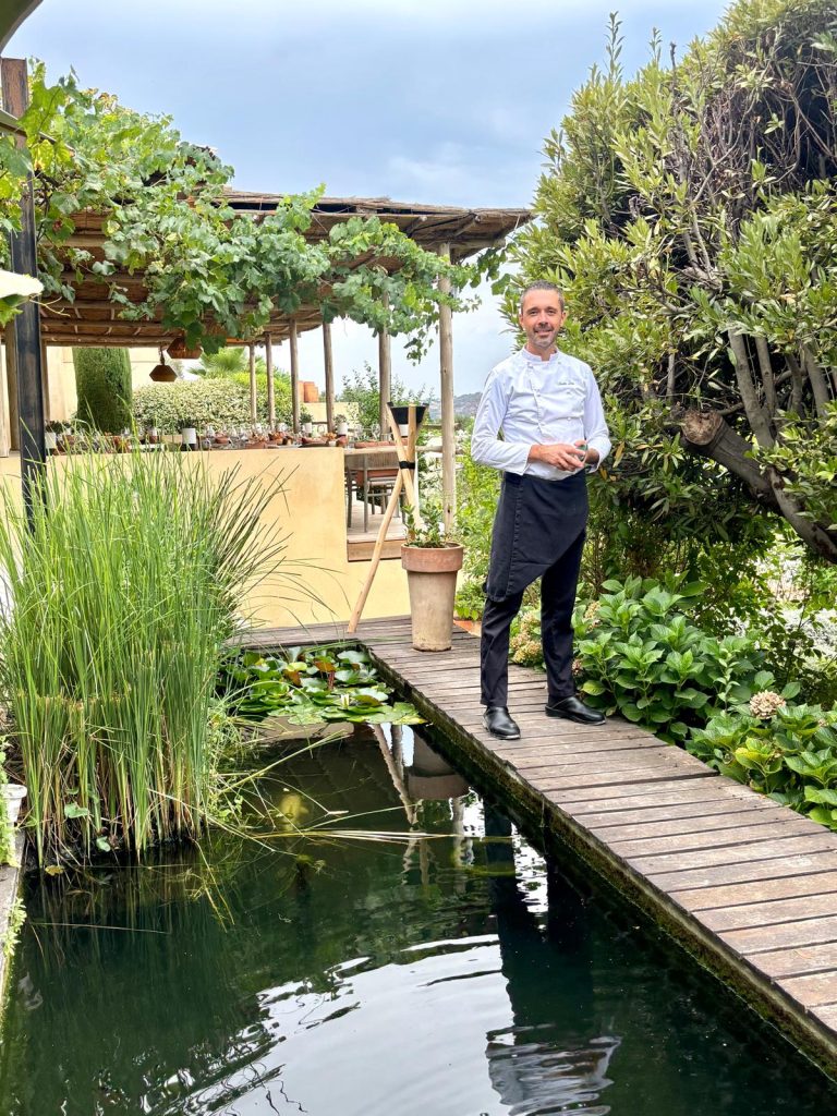 Le restaurant Toile Blanche et ses tables à l'extérieur dans un cadre champêtre très arboré avec le chef Nicolas Leclair en chemise.