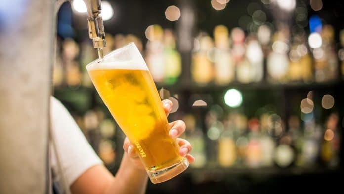Un barman sert une pinte de bière derrière son comptoir.