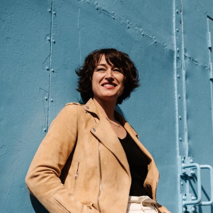 Cécile Kopp la nouvelle directrice du MAMAC de Nice prend la pose adosée à un mur.
