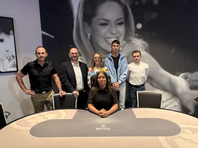 Plan large de la directrice de la formation, du responsable des jeux du casino ainsi que trois anciens élèves derrière une table de poker.