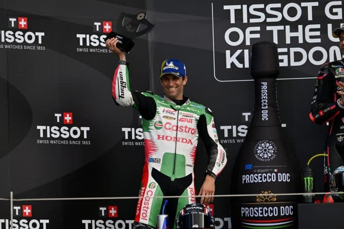 Le pilote Cannois en MotoGP, Johann Zarco soulève un trophée sur un podium.