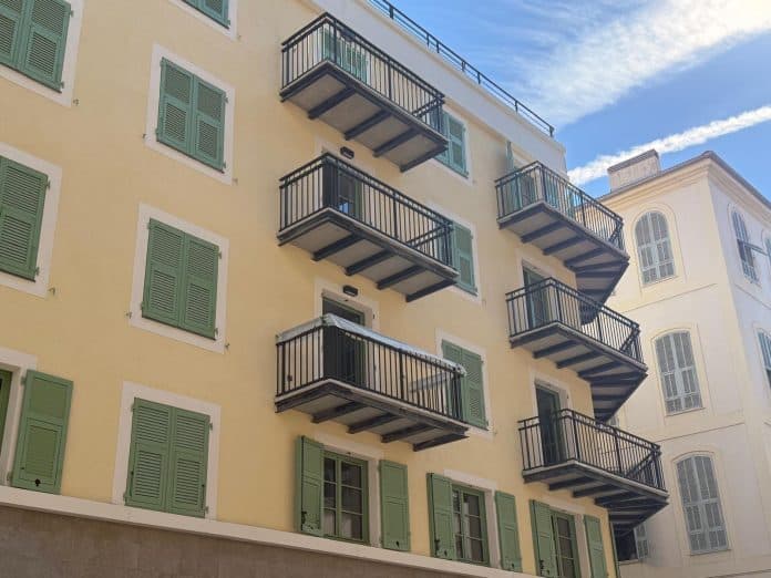 Le nouveau bâtiment de la Villa Candide avec des petits balcons une façade jaune et volets vert.