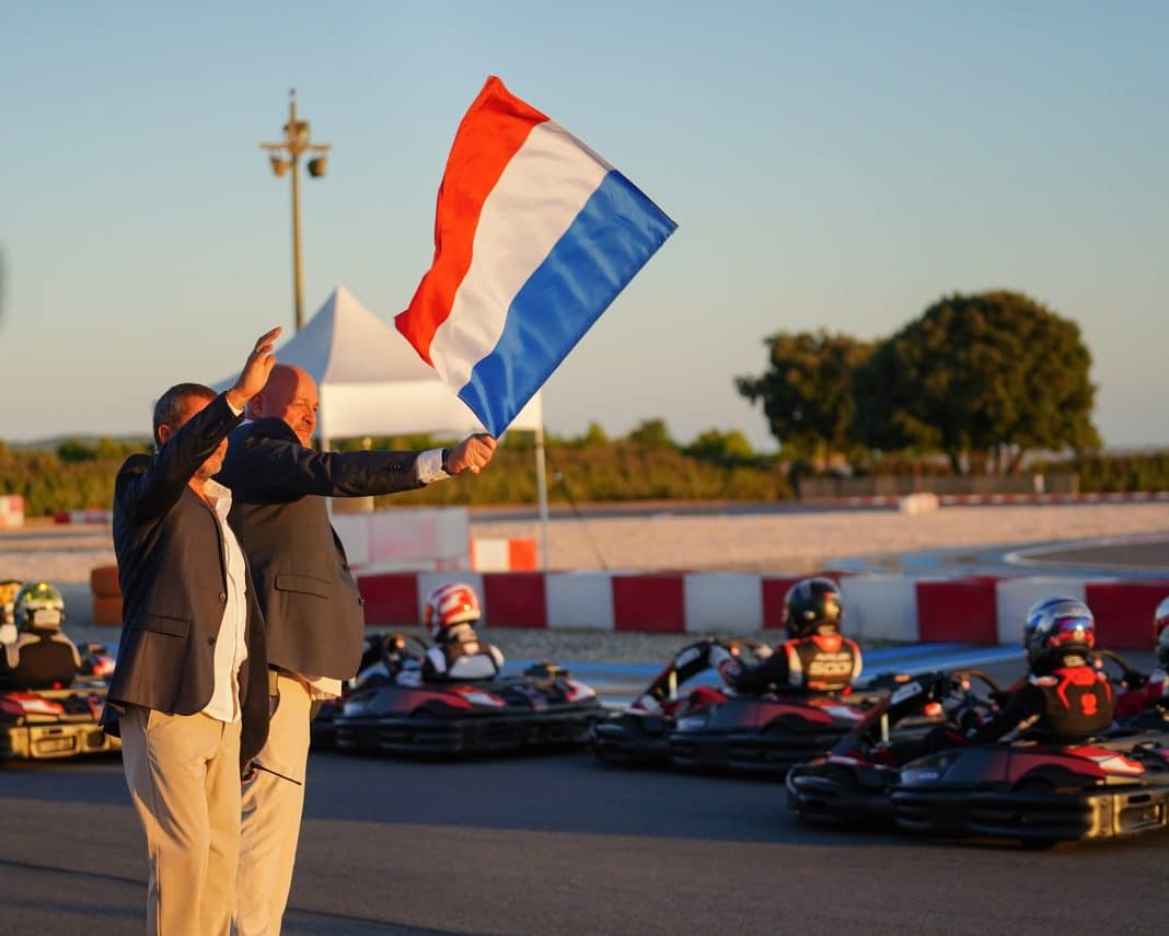 Philippe Bianchi au bord de la piste agite un drapeau français pour donner le départ de la course avec les pilotes dans les karting.