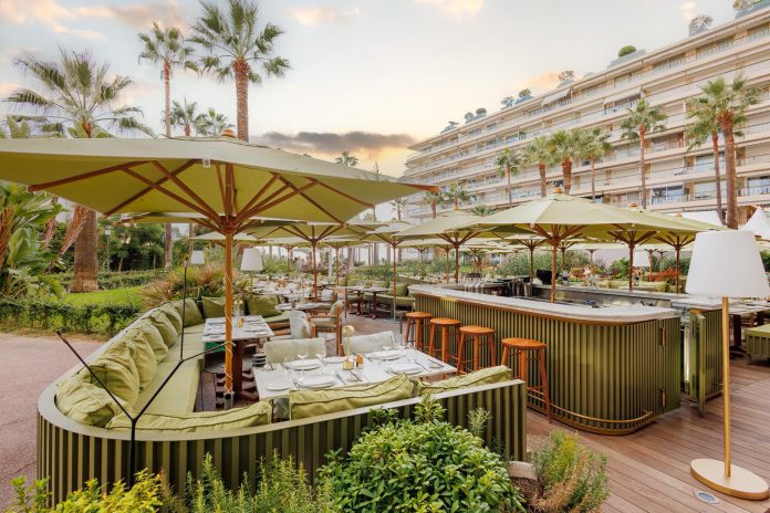La terrasse du restaurant Mr Nakamoto tout en bois avec des parasols blanc et de la verdure.
