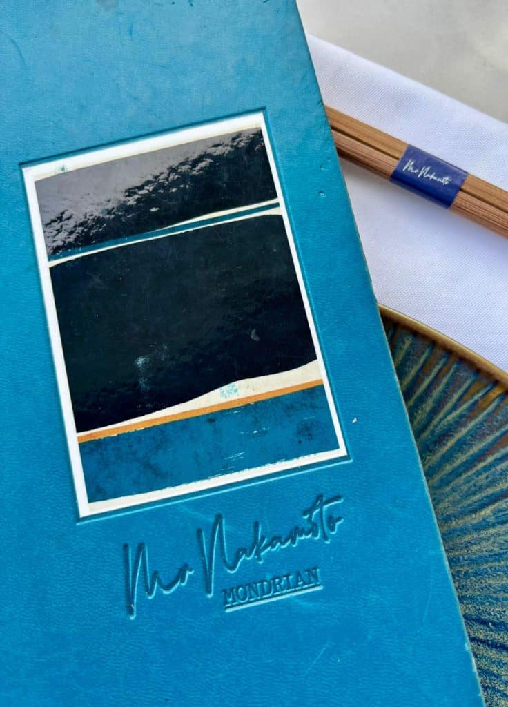 La carte du restaurant Mr Nakamoto bleu avec une photo artistique représentant la mer au centre