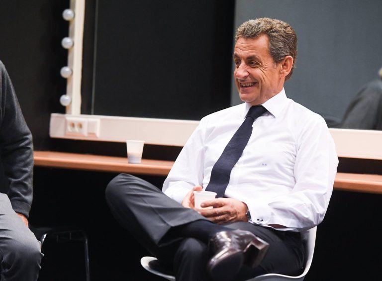 L'ancien président de la République Nicolas Sarkozy en chemise blanche cravate foncée assis sur une chaise