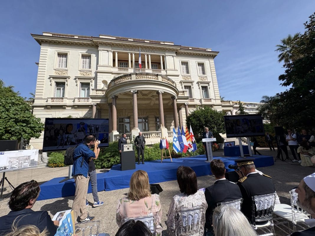 Plan large de la scène où se trouve Christian Estrosi et Éric de Rothschild. Deux télés sont exposés pour diffuser le mini-film du projet du Mémorial de la Shoah à Nice.