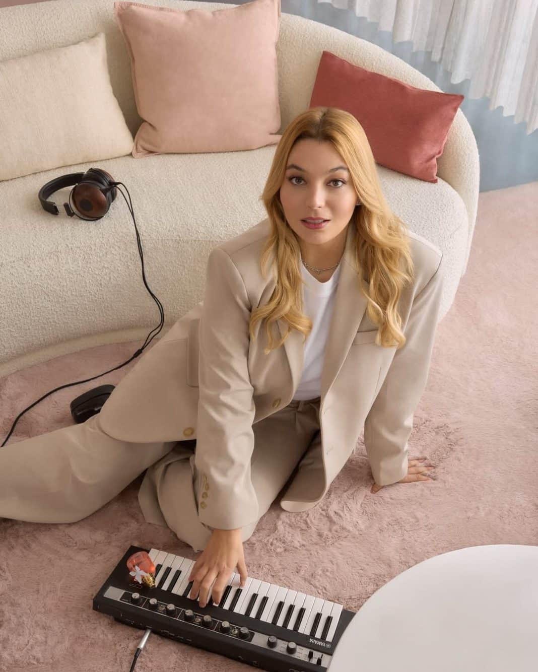 La chanteuse Santa en costume, la main gauche sur un petit piano, marraine du Téléthon 2025