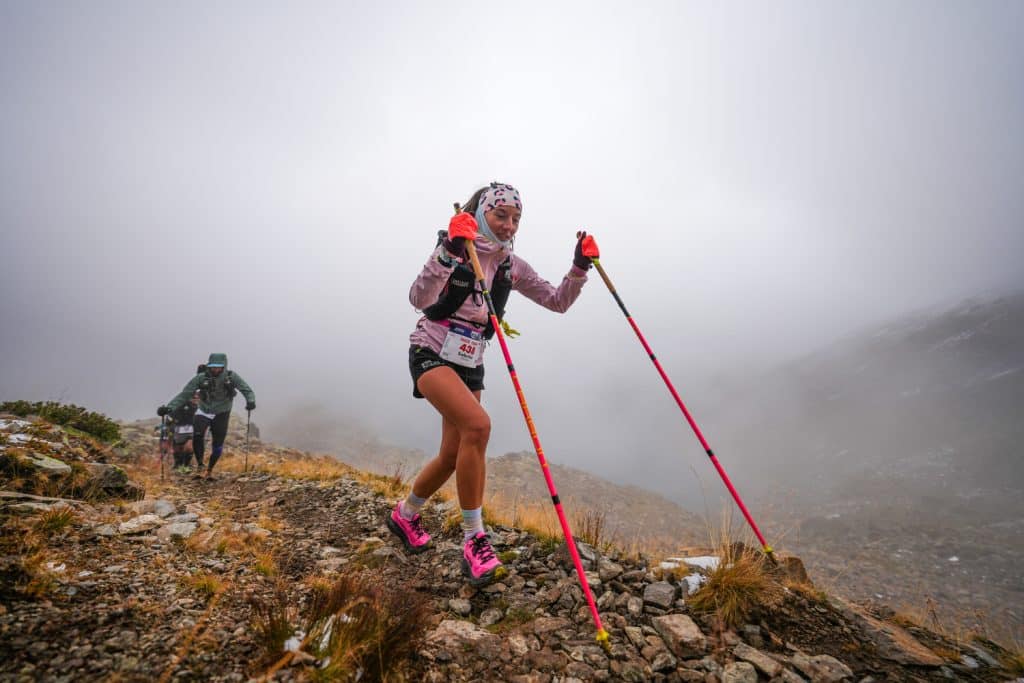 Un coureur le long d'un chemin en gravier avec des bâtons dans le brouillard.