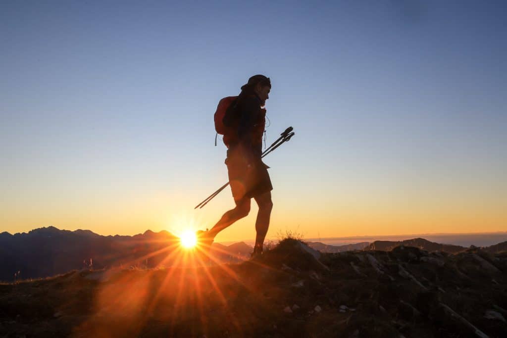 Un participant dans la montagne en fin de journée avec le soleil couchant.