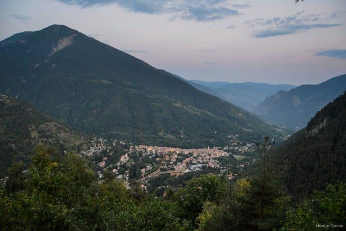 Une vue de la Vallée de la Vésubie avec des forêts, des montagnes et un village enclavé.