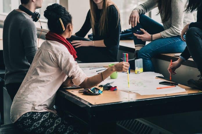 Des étudiants en train de réviser des cours en cercle avec des feuilles, cahiers, stylos, ordianteurs...