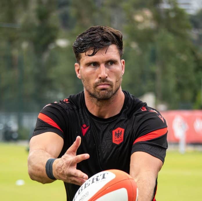 Un joueur de Nissa Rugby à l'échauffement dans les couleurs traditionnelles noir et rouge en train de faire une passe.