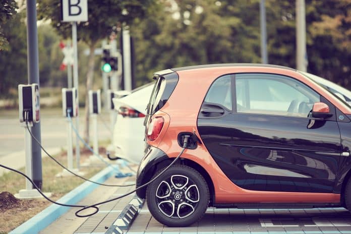 une voiture électrique se recharge grâce à une borne reliée par un câble.