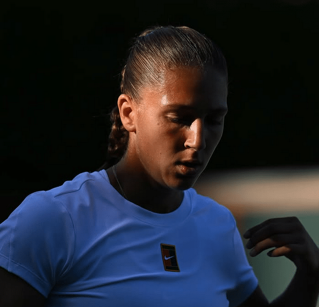 La joueuse de tennis Niçoise Diane Parry en blanc dans l'ombre, la tête basse.