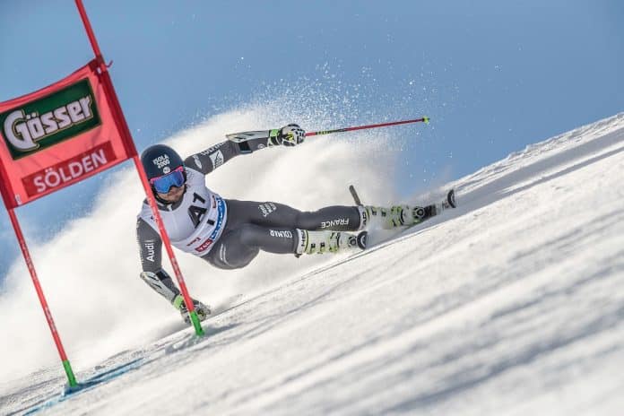 Le skieur Niçois Mathieu Faivre sur la piste vise une porte rouge dans sa trajectoire en pleine courbe.