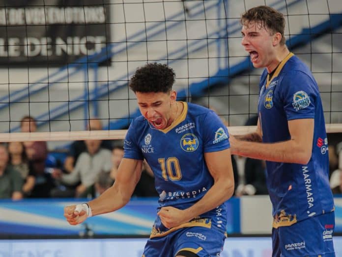 Les joueurs du Nice Volley Ball serrent le poing après avoir marqué un point. Ils sont habillés en bleu avec des liserés jaunes sur le maillot.