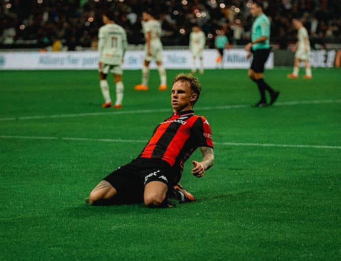 Un joueur de l'OGC Nice glisse sur la pelouse pour célébrer un but.