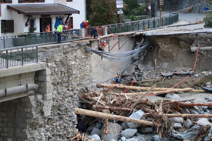 Un pont détruit par la tempête Alex avec des personnes suspendues au pont pour tenter de le sécuriser et le réparer.