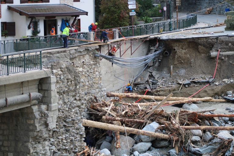 Un pont détruit par la tempête Alex avec des personnes suspendues au pont pour tenter de le sécuriser et le réparer.
